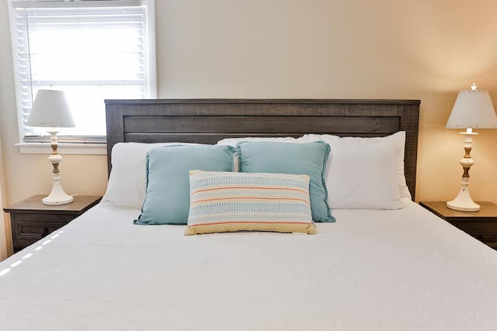 Dormitorio principal con cama tamaño king, cómoda y 2 mesitas de noche con TV inteligente de 55 pulgadas.