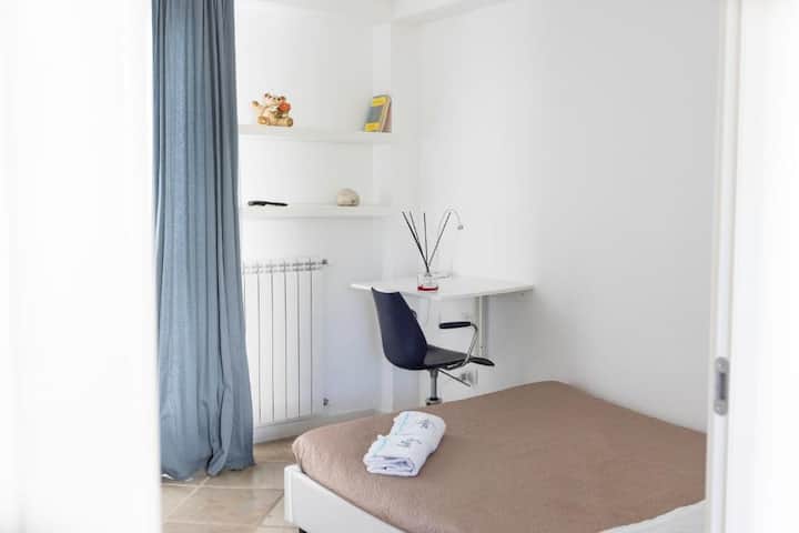 غرفة نوم ثانية في الطابق الأول، كاملة مع خزانة كبيرة ومكتب للتنظيم، وسرير مزدوج مريح وإمكانية الوصول المباشر إلى الشرفة والتراس، مما يوفر بيئة مريحة ومشرقة للراحة والاسترخاء.