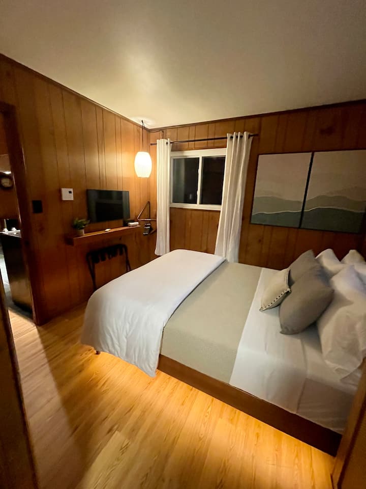 إطلالة على غرفة النوم الرئيسية من الحمام، في الأفق، هو سرير بحجم كوين وتلفزيون سامسونج الذكي