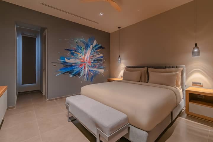 3e slaapkamer, een kingsize bed, een gloednieuwe 65 inch tv, een eigen badkamer en een uniek muurkunstwerk.