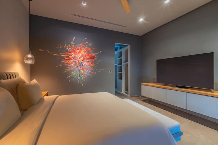 4e slaapkamer, een kingsize bed, een gloednieuwe 65 inch tv, een eigen badkamer en een uniek muurkunstwerk.