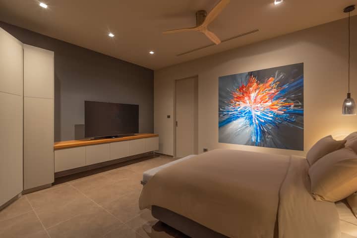 1e slaapkamer, een kingsize bed, een gloednieuwe 65 inch tv, een eigen badkamer en een uniek muurkunstwerk.