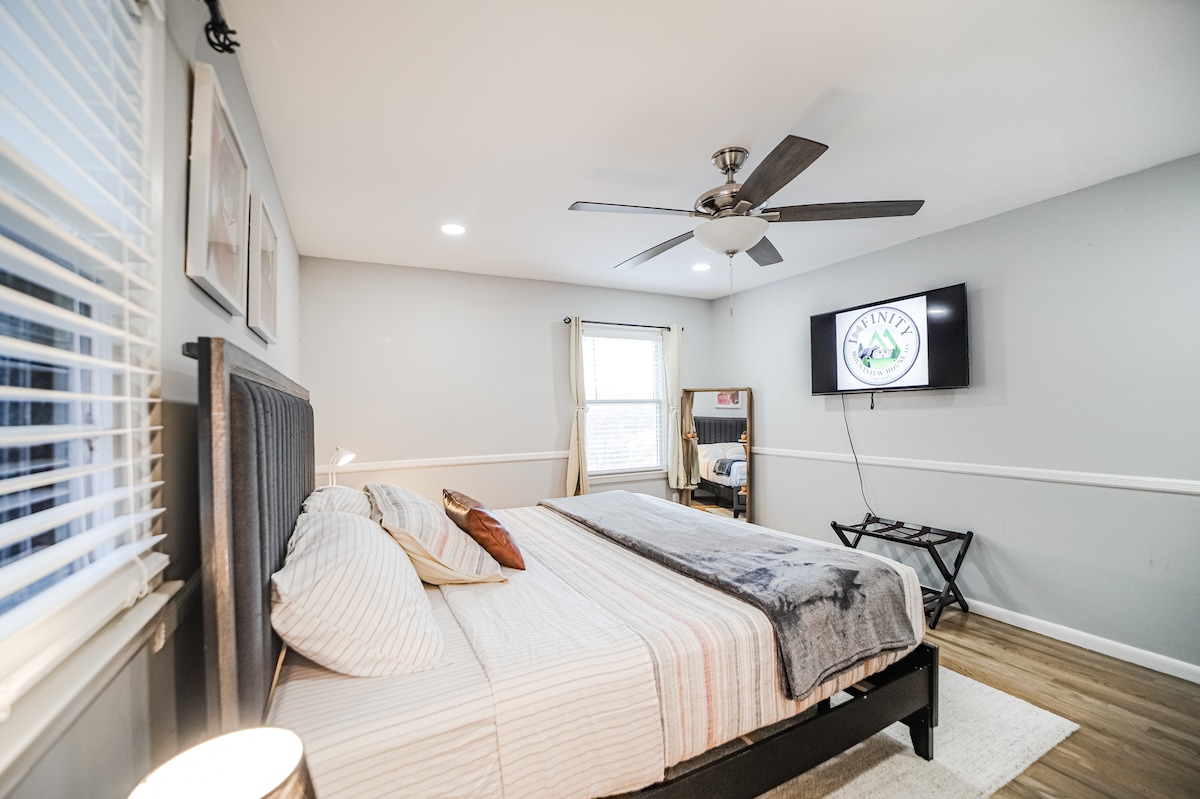 El dormitorio principal tiene una cama tamaño king con dos mesitas de noche, una lámpara con un cargador portátil, un televisor inteligente de 55 pulgadas y un baño completo.