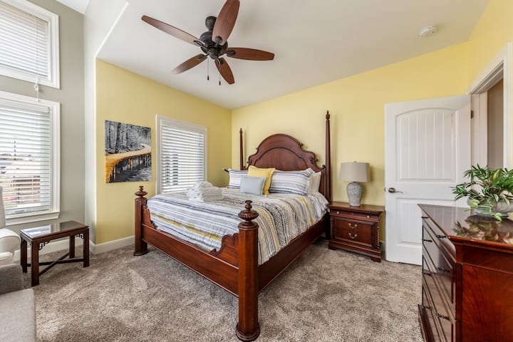 غرفة نوم دافئة وجذابة للضيوف مع سرير من الخشب الصلب وبياضات ناعمة وإضاءة طبيعية.