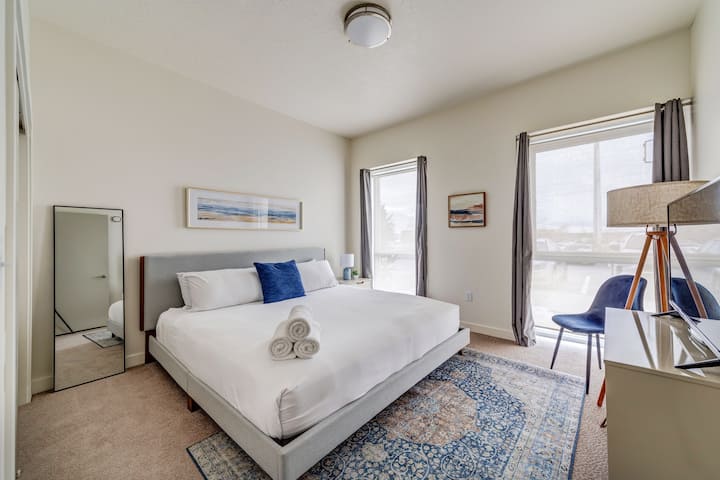 سرير بحجم كينغ وستائر سوداء وتلفزيون روكو 43بوصة ومرآة لكامل الجسم. تقع الخزانة كاملة الحجم على يسار المرآة. 