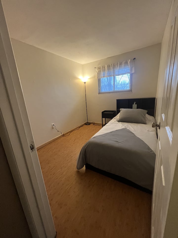 Hay un pequeño dormitorio adecuado para una persona que tiene una cama doble, armario y mesa de noche.