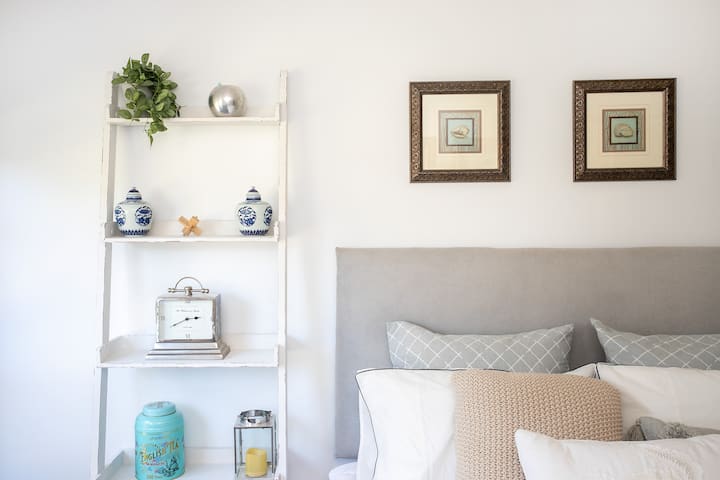 Un espacioso dormitorio secundario secundario con una cómoda cama queen decorada con el estilo Hamptons en mente.  La habitación cuenta con persianas 100% bloqueadas para la noche de sueño perfecto.