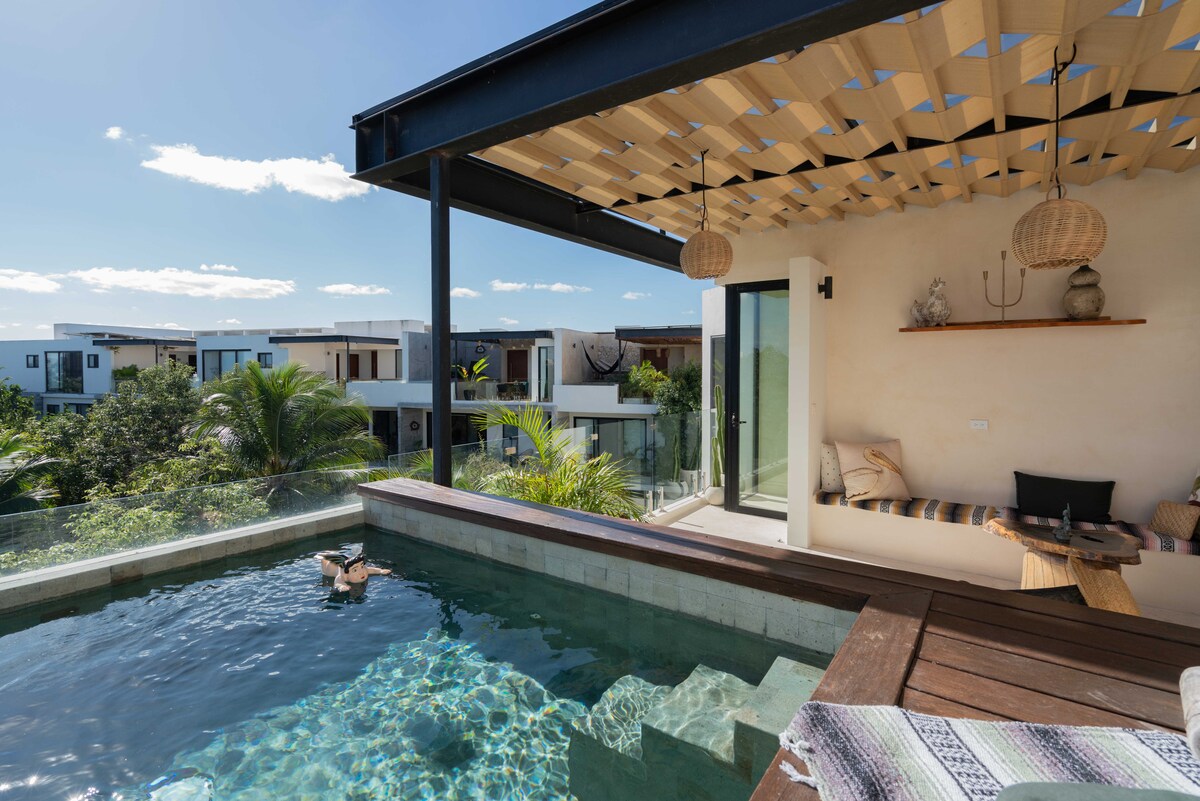 A private pool is nestled on a terrace, offering panoramic views of the surrounding area. Sunlight reflects off the water, while a cozy seating area is seen nearby. Natural materials contribute to a relaxed atmosphere, enhancing the outdoor space for leisure and enjoyment.