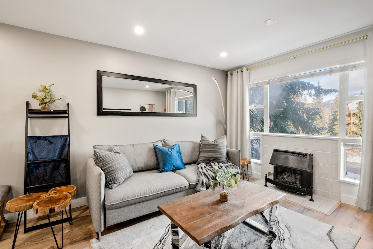 Living room containing a couch (that turns into a double bed), a coffee table, fireplace mirror and side table.