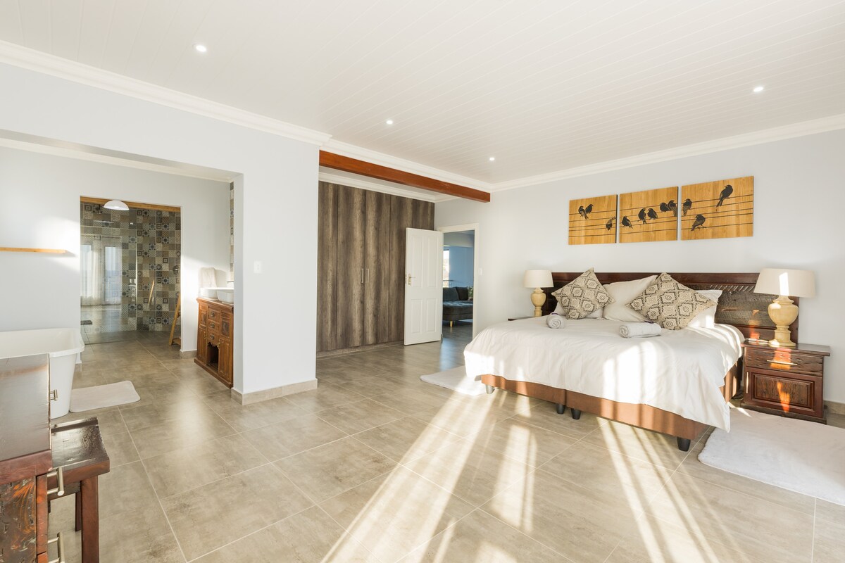 Chumba kikuu cha kulala kilicho na nafasi ya kutosha ya kabati na bafu la chumbani lenye matembezi makubwa kwenye bafu na beseni la kuogea lililosimama bila malipo