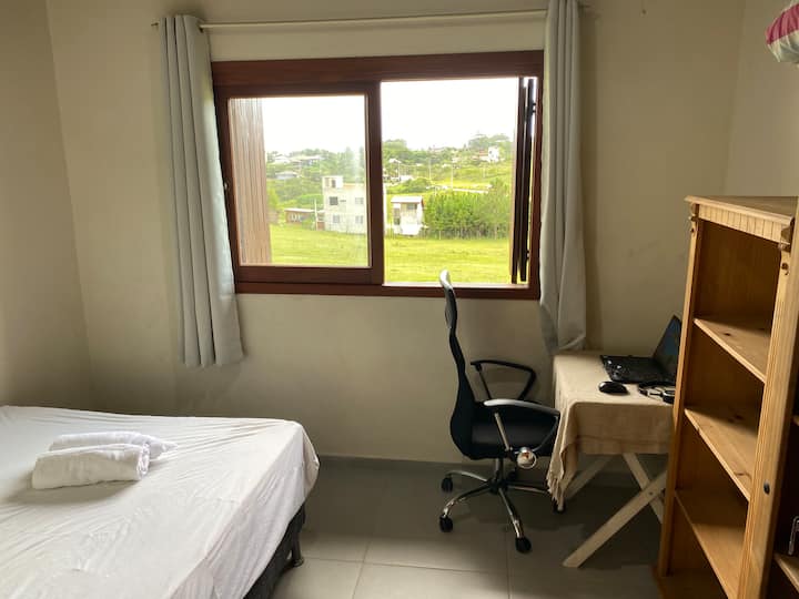 חדר עם מיטה זוגית ומשרד עבודה מרוחק, המשקיף על חווה מאחור עם פרות ואווירה טובה.
