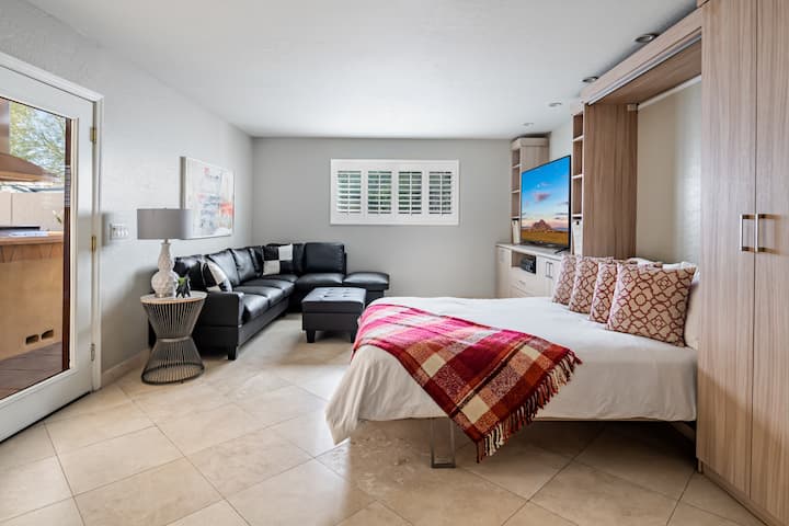 Suite de invitados versátil con una cama abatible de primera calidad y armarios California personalizados. Este espacio multifuncional incluye una sala de estar privada con televisor inteligente y acceso directo a la cocina al aire libre y al patio a través de puertas francesas de vidrio.