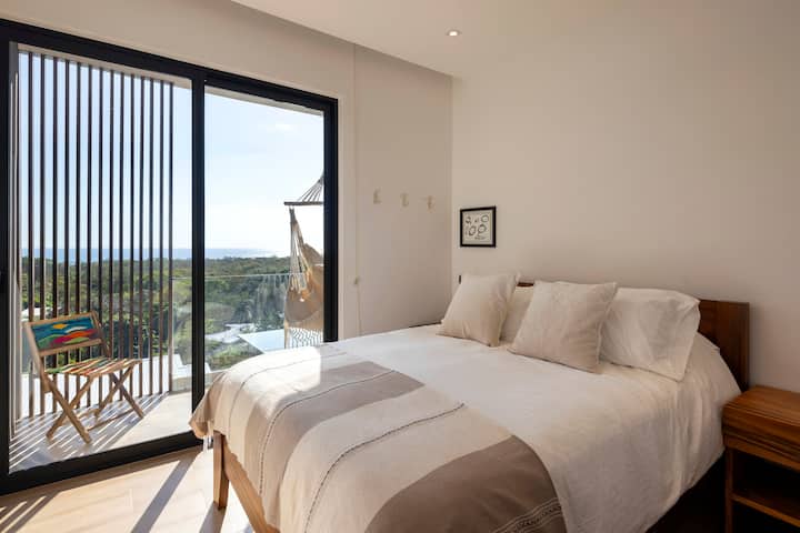 Втора спалня на горния етаж с двойно легло и балкон с изглед към океана