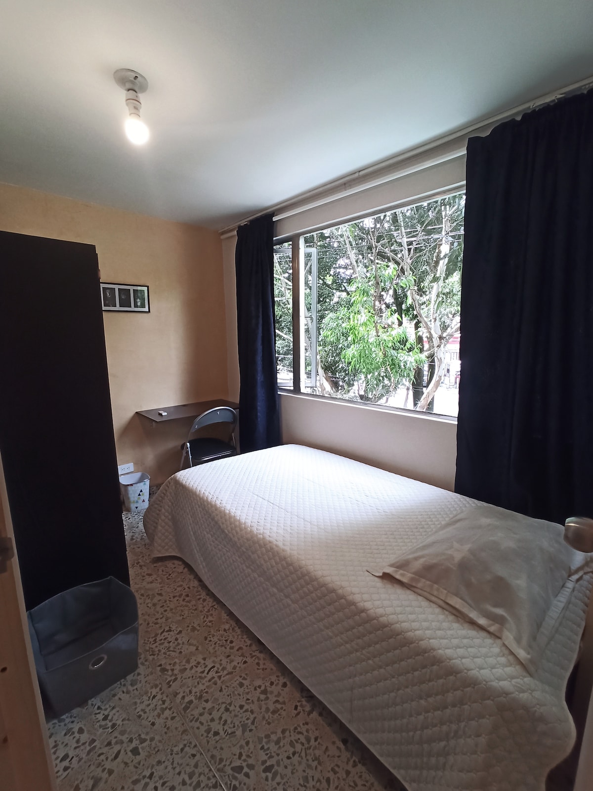 Zimmer mit einfachem Bett, Schrank und Schreibtisch. 