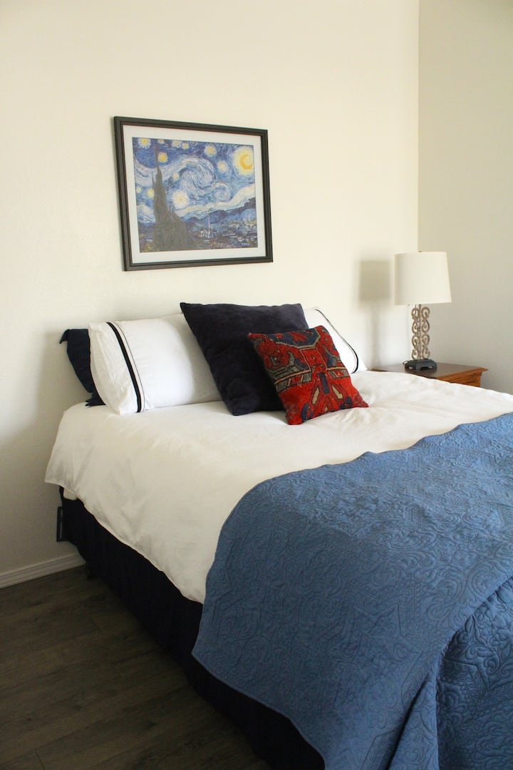 Დედოფლის ზომის საწოლი კომფორტული ბამბის თეთრეულით, რომელიც აღჭურვილია სააბაზანოთი.  Დიდი საგარდერობო ზღურბლის გარეშე