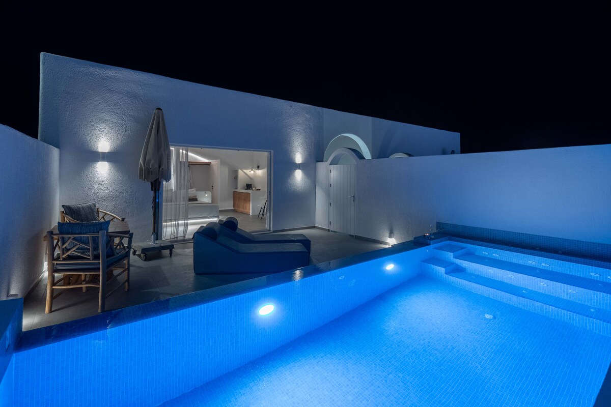 A private terrace features a jetted pool illuminated with soft blue lighting. Comfortable seating options are visible nearby. The entrance to the suite reveals a spacious interior, with soft hues enhancing the overall ambiance. The walls are painted in a bright, clean color.