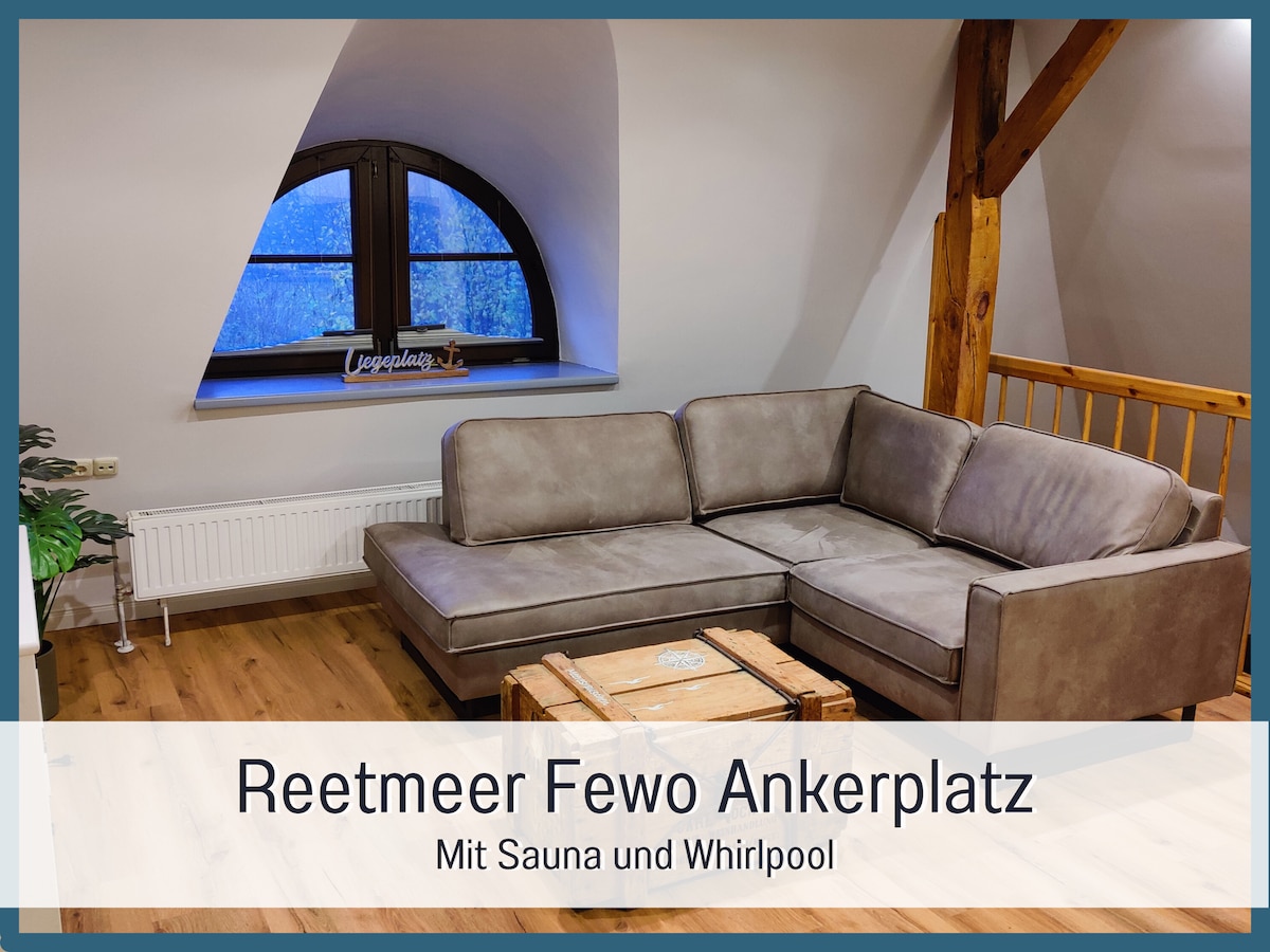 A spacious living area is furnished with a large, comfortable sofa arranged around a rustic coffee table. Exposed wooden beams add character to the ceiling, while a large window offers natural light and views. A small console table is positioned nearby, enhancing the ambiance.