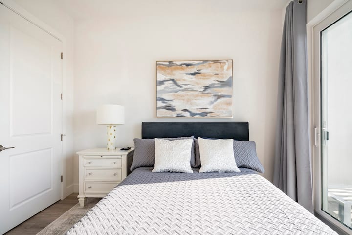 habitación de invitados con cama tamaño queen con puertas correderas de vidrio que conducen al balcón y un armario grande para el almacenamiento
