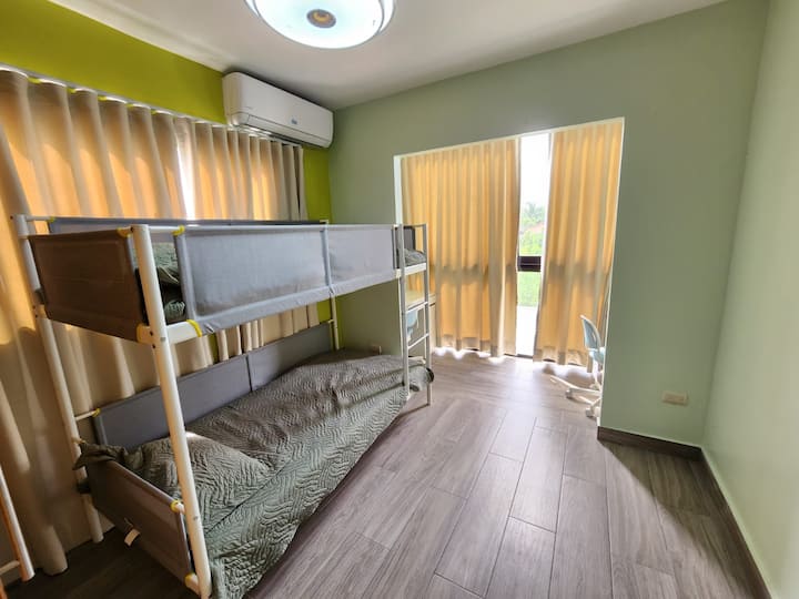 Chumba cha kulala cha wageni kilicho na maeneo mawili ya kazi ya mbali na sakafu hadi kwenye madirisha ya dari.