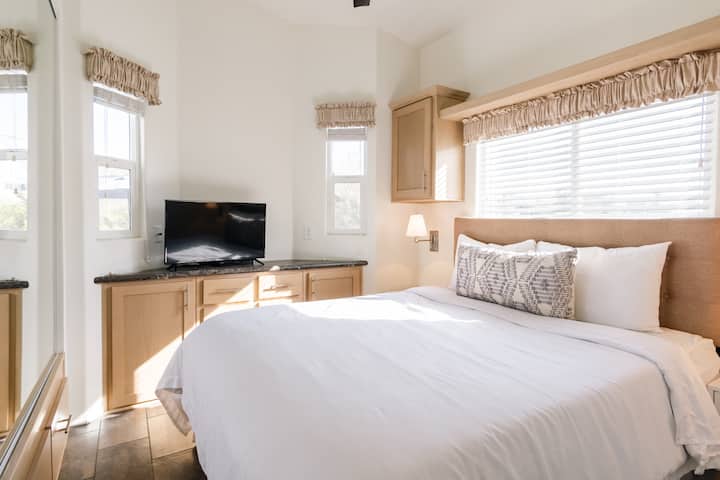 Slnečná spálňa vybavená televízorom, manželskou posteľou a úložným priestorom.