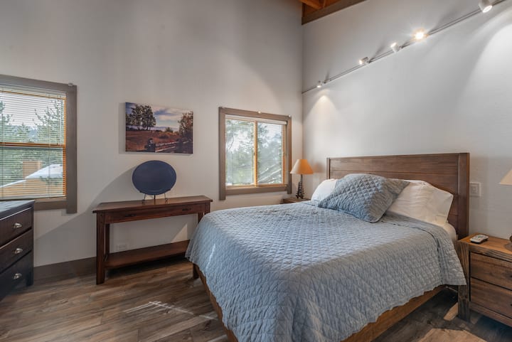 Dormitorio principal con techo abovedado con iluminación de pista. El maestro tiene ropa de cama, pisos y muebles nuevos. Ropa de cama de granero de cerámica.