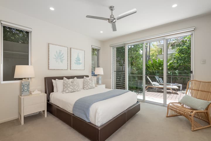 La suite de invitados de la planta baja tiene una cama tamaño queen, baño privado, batas incorporadas y entrada a la piscina