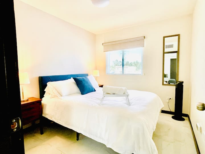 Acogedora recámara con cama Queen y colchón memory foam para un descanso reparador. Equipada con lámparas de noche, ventilador de torre, espejo de cuerpo completo y bandeja de bienvenida con toallas. Espacio cómodo para relajarte durante tu estancia.