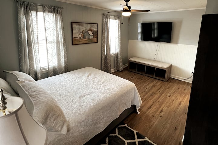 Dormitorio principal con una cama tamaño queen y un televisor Fire de 55 pulgadas.