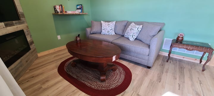 Простор во дневната соба со брачен кауч на спуштање, телевизор и електричен камин.