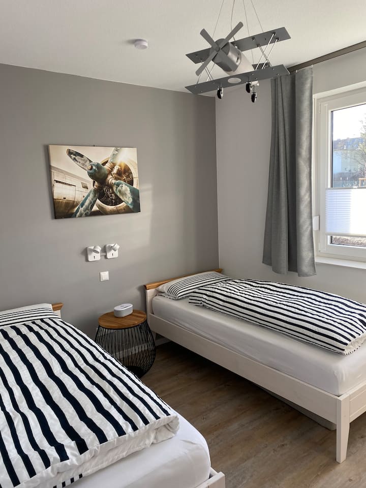 ห้องนอนเตียงเดี่ยว 2 เตียงตู้เสื้อผ้าโต๊ะทำงานขนาดเล็กพร้อมเก้าอี้ทีวีและนาฬิกาปลุกวิทยุ