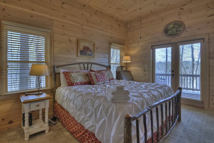 La chambre king size au niveau inférieur dispose d'une télévision à écran plat et de portes-fenêtres menant à un coin salon sur la terrasse du bas avec vue sur la rivière.