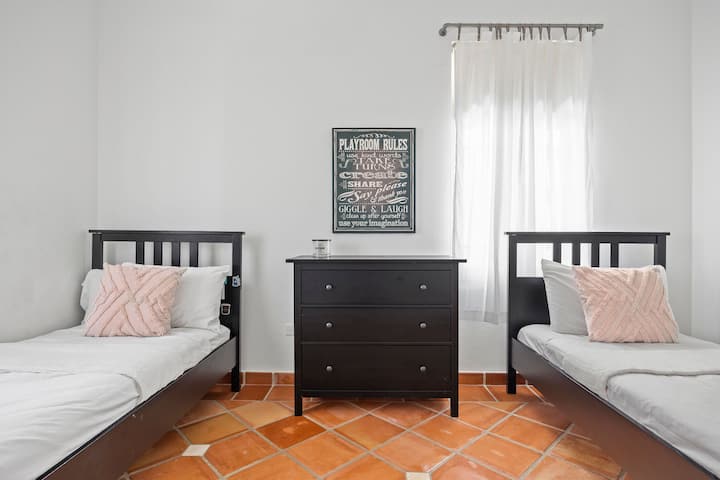 Dormitorio luminoso con dos camas individuales, ideal para camas flexibles.