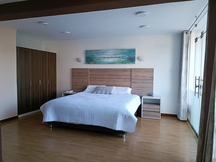 hlavná izba s manželskou posteľou King, výhľadom do záhrady a priestrannými manparami na prirodzené osvetlenie.