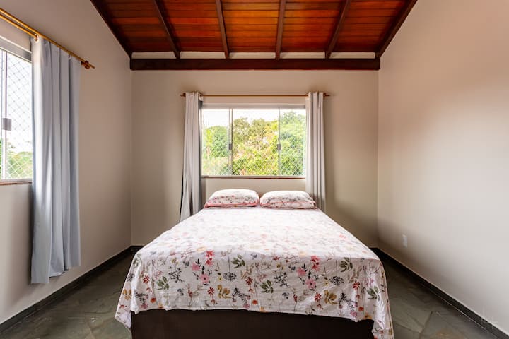 Room with double bed on the 1st floor and front view of the farmhouse.