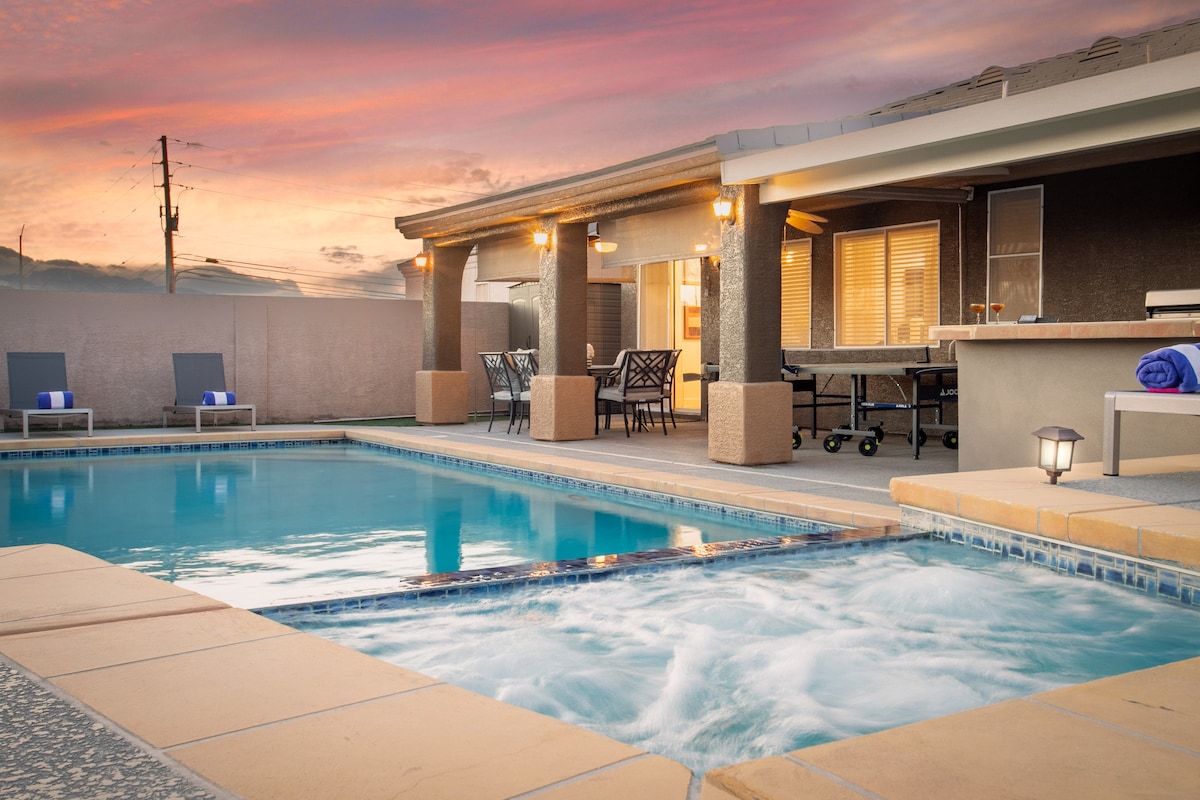 A private backyard area features a newly built pool and spa, set against a backdrop of a colorful sunset. Comfortable loungers are positioned nearby, while a dining table and BBQ grill stand ready for outdoor gatherings.