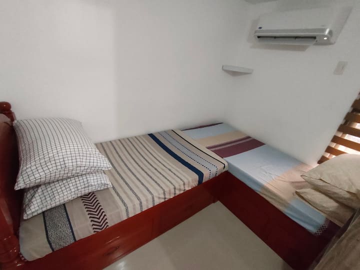 Cadre de lit en bois élégant en L avec 2 lits. Climatisation de type réparti dans la chambre 2. Linge de lit de qualité, avec de bons oreillers et couettes.