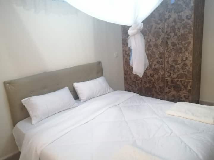 dormitorio principal con televisión, inodoro, baño, armario y mesa de estudio y silla de estudio