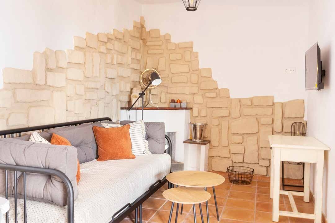 La sala de estar tiene un sofá estilo cama de día y televisión montada en la pared.