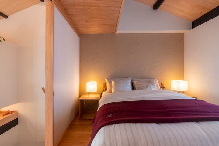 Bedroom stucco walls, just a few lights on both sides, and a comfortable qu-in-size bed