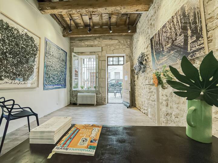 Galería/espacio comercial con iluminación de galería y sistema colgante de cimaises. Escritorio plegable y 4 sillas maestras Kartell. Gran escalera plegable y tabla de sándwiches junto a la carretera.