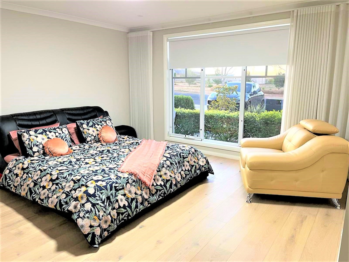 ห้องนอนใหญ่พร้อมเตียงหนังหรูและโซฟาพร้อมวิวสวนด้านหน้า