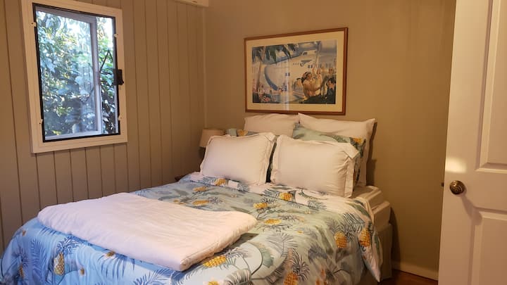 Cozy bedroom with queen sized bed and views of the ginger garden and outdoor shower.