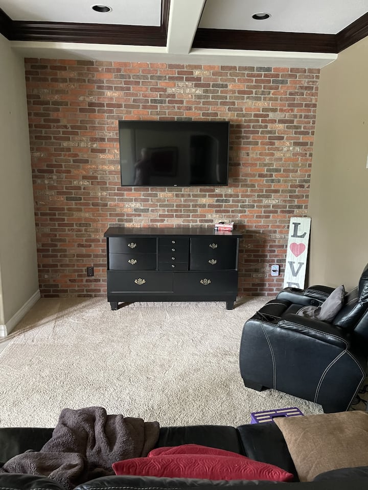 Черен кожен диван и масажен стол в бърлогата за удобни нощи при гледане на любимия ви филм на смарт телевизора.