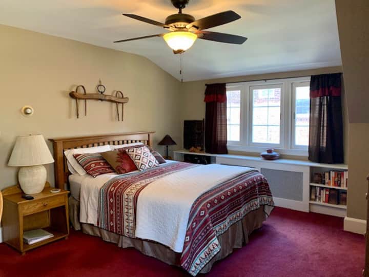 The bright and spacious second floor master bedroom has a queen bed, flat screen TV, a large closet, desk, dresser, and attached bath with shower.