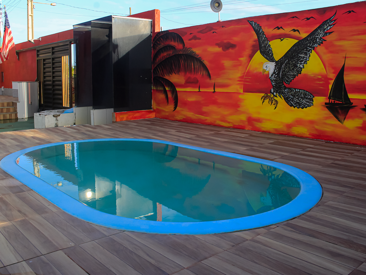 An inviting outdoor pool is surrounded by wooden flooring, reflecting the vibrant colors of a mural depicting an eagle soaring across a sunset. Nearby, elements of local art enhance the relaxing ambiance of the space.