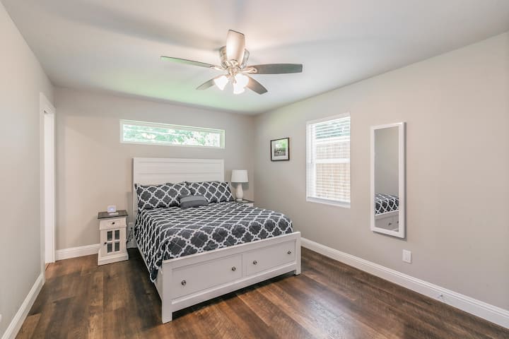 Dormitorio principal grande con cama tamaño queen, televisor montado en la pared y baño completo.