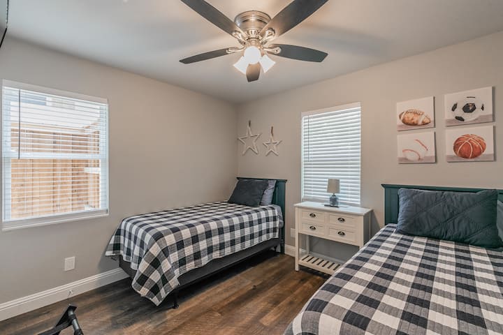 Dormitorio del medio con dos camas individuales y un televisor montado en la pared.