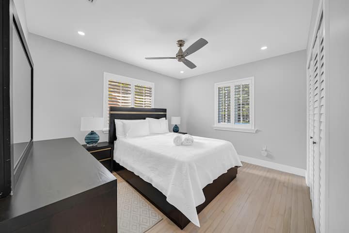 N.º2 dormitorio de invitados grande con cama tamaño queen recientemente comprada, ventilador de techo, mesas auxiliares y armario personalizado.