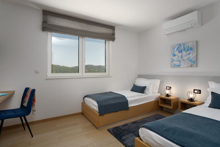 Segunda habitación con dos camas individuales y TV inteligente.