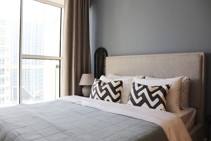 Მყუდრო საძინებელი 1-საძინებლიან მოკლევადიან გაქირავებაში მეიფაირში, ბიზნეს-ბეიში. Აქ არის კომფორტული საწოლი, ელეგანტური დეკორი და იატაკიდან ჭერამდე ფანჯრები ქალაქის ხედებით. Იდეალური დასასვენებელი სახლი დუბაიში დასვენებისთვის.